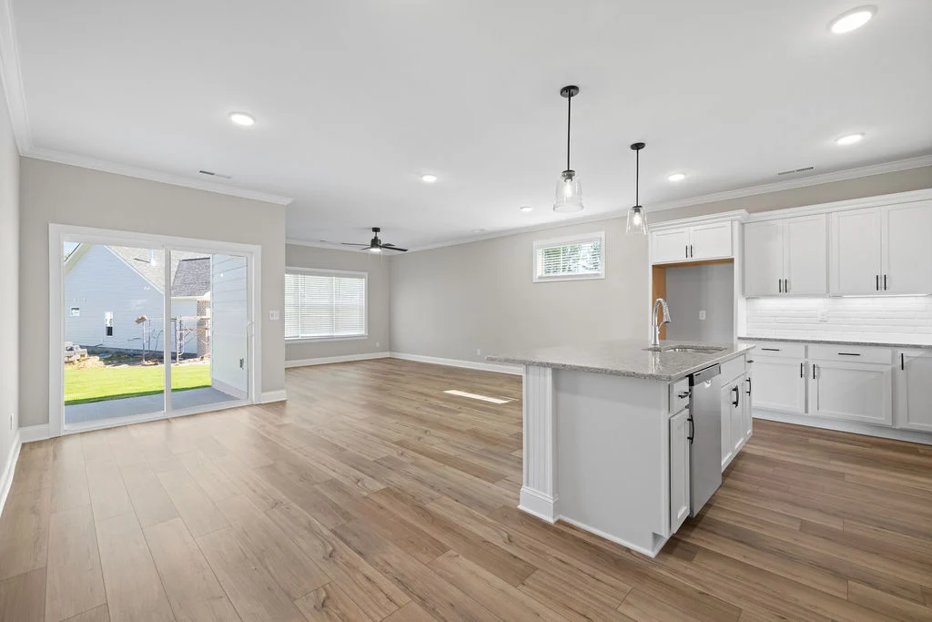 Open-concept living area by Pratt Home Builders in Chattanooga, TN, featuring a modern kitchen with island, pendant lights, and sliding glass doors.