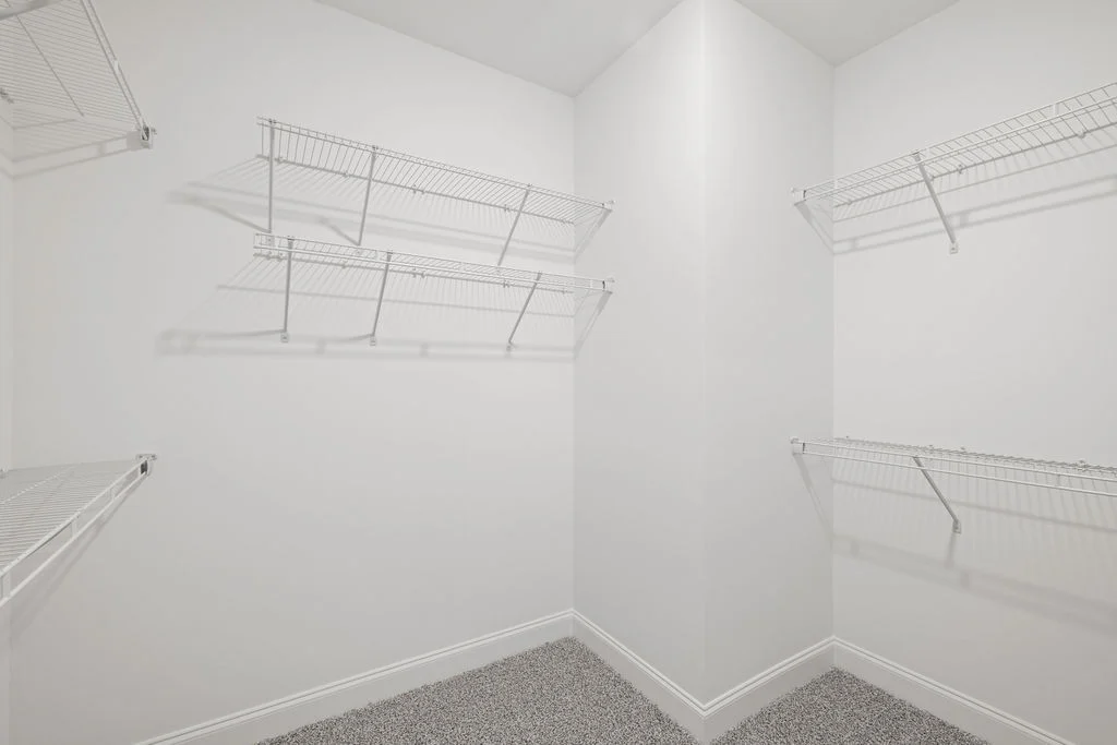 Spacious walk-in closet with wire shelving and carpet flooring by Pratt Home Builders in Chattanooga TN.