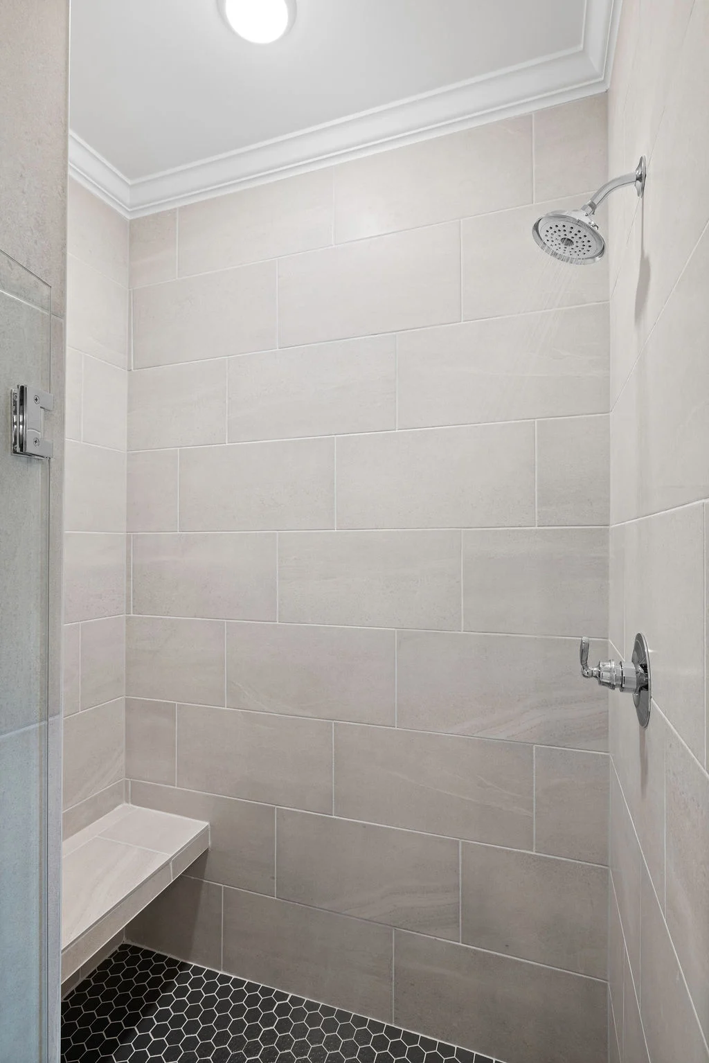 Spacious, modern tiled shower with stone bench and chrome fixtures by Pratt Home Builders in Chattanooga, TN.