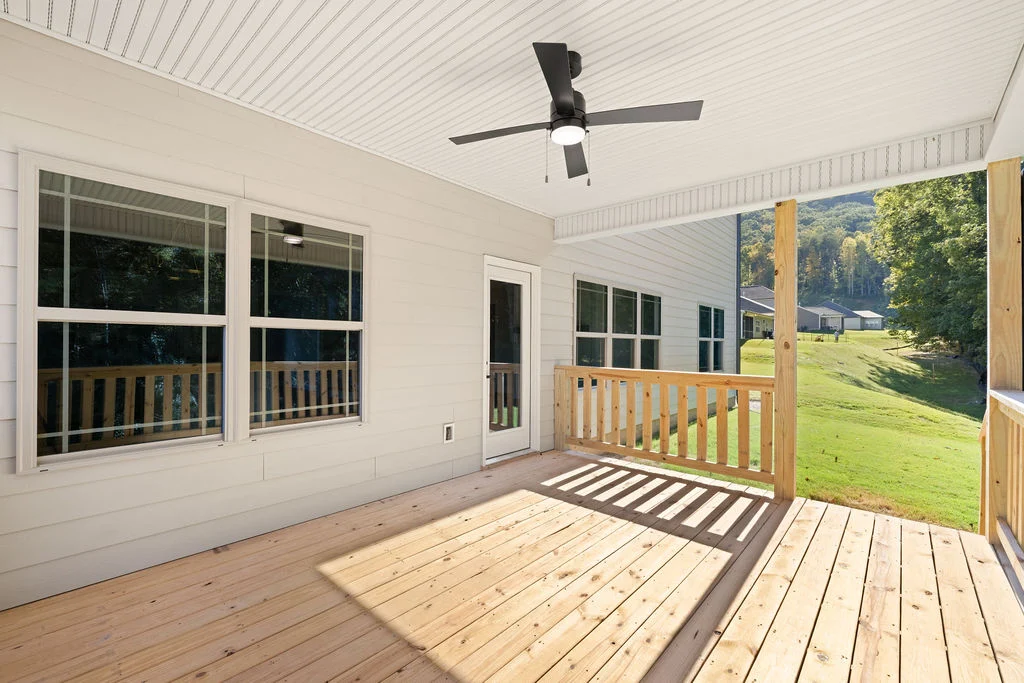 Spacious wooden patio with ceiling fan and scenic backyard view, designed by Pratt Home Builders in Chattanooga TN.