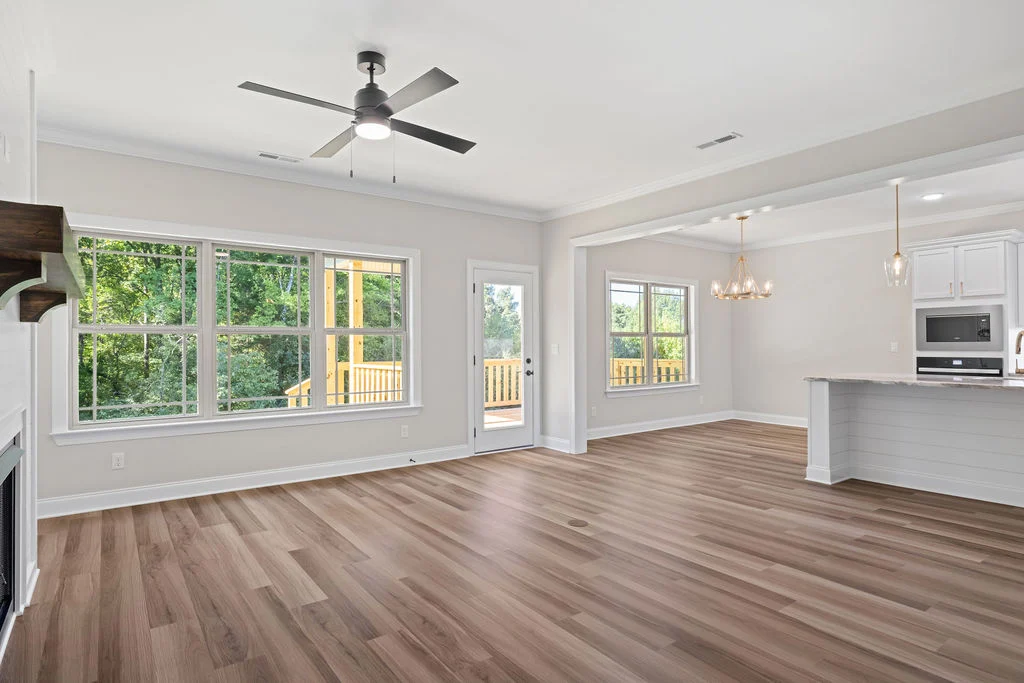 Spacious open-concept living area with hardwood floors, large windows, modern kitchen, and patio access by Pratt Home Builders in Chattanooga TN.