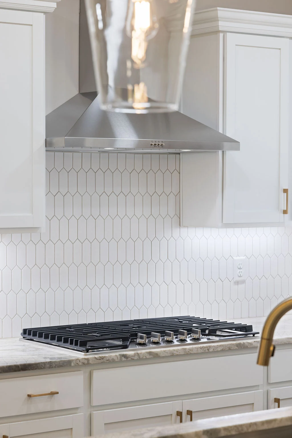 Modern kitchen with white hexagonal tile backsplash, stainless hood, and gas stove by Pratt Home Builders in Chattanooga TN.