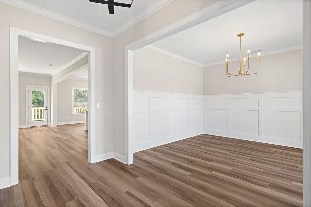 Bright dining room with wood flooring, wainscoting, and gold chandelier, built by Pratt Home Builders in Chattanooga, TN.
