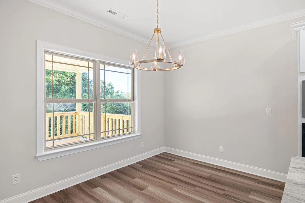 Dining room with large window, modern chandelier, hardwood floors, and bright natural light, built by Pratt Home Builders in Chattanooga TN.