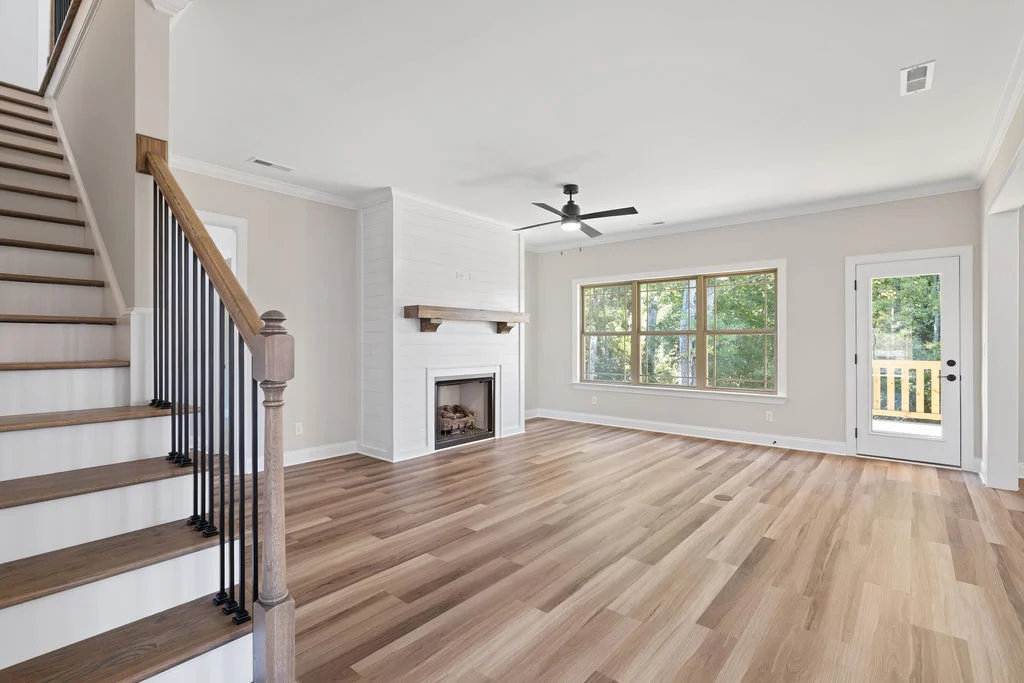 Spacious living room with hardwood floors, fireplace, and large windows. Stairs on the left. Built by Pratt Home Builders in Chattanooga TN.