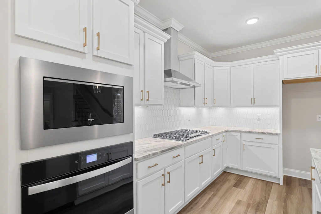 Modern kitchen with white cabinets, stainless steel appliances, and marble countertops. Designed by Pratt Home Builders in Chattanooga TN.