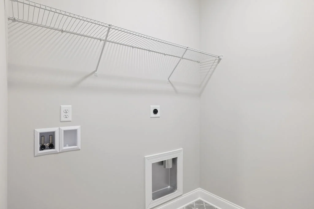 Laundry room with wire shelf, electrical outlets, and plumbing hookups, designed by Pratt Home Builders in Chattanooga TN.