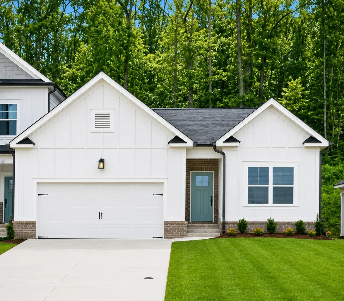 Single-story white house with attached two-car garage, green door, and manicured lawn by Pratt Home Builders in Chattanooga TN.