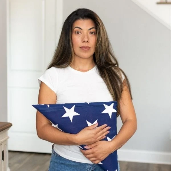 Person holding a folded American flag, standing indoors, symbolizing patriotism. Pratt Home Builders in Chattanooga TN.