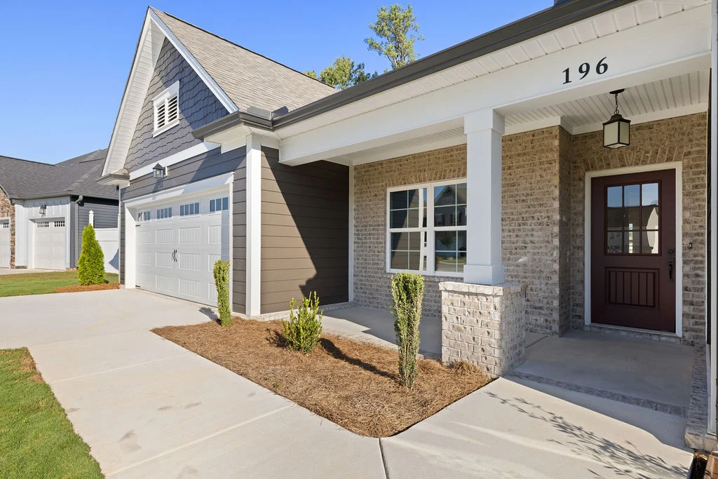 Modern house with brick facade and a front porch. Features white garage door and columns. Crafted by Pratt Home Builders in Chattanooga TN.