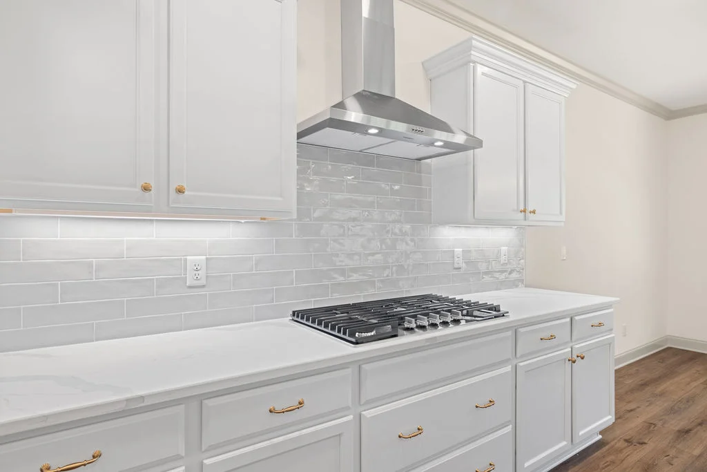 Bright kitchen with white cabinets, gold hardware, and a sleek gas cooktop by Pratt Home Builders in Chattanooga TN.