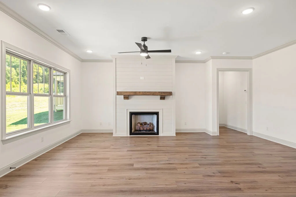 Spacious living room with large windows, fireplace, and wood floors by Pratt Home Builders in Chattanooga TN.