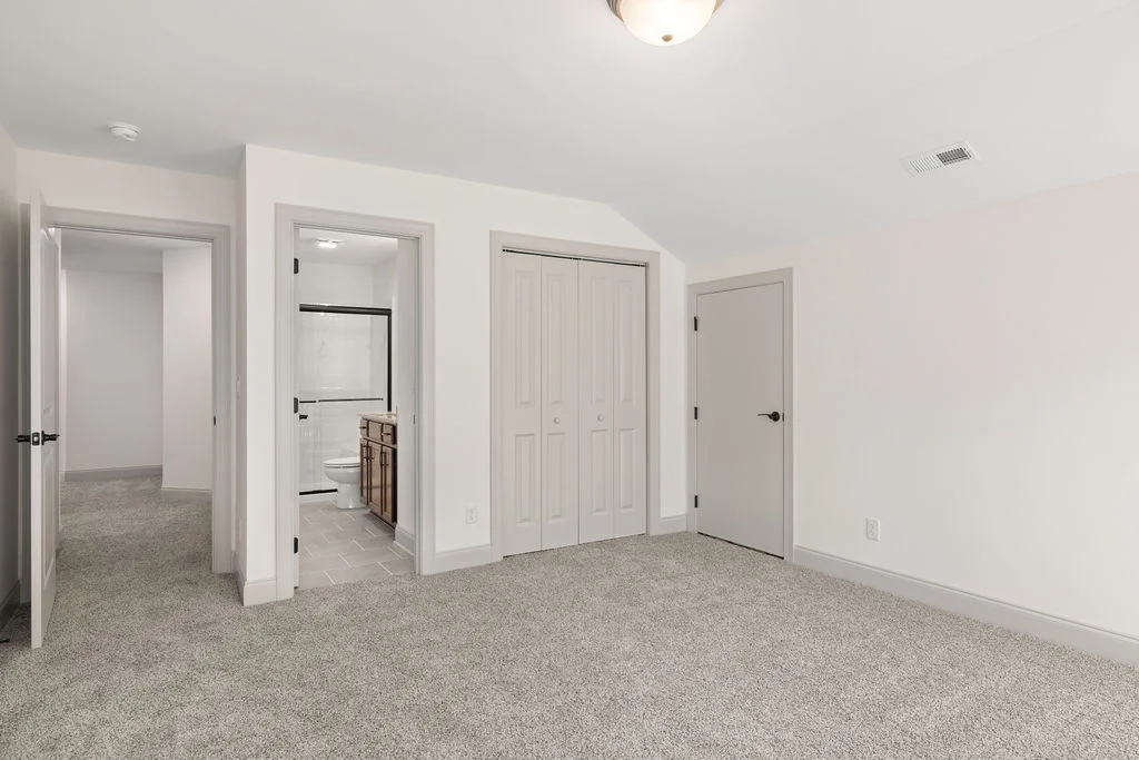Carpeted room with beige walls, connecting doors, and an adjoining bathroom, built by Pratt Home Builders in Chattanooga TN.