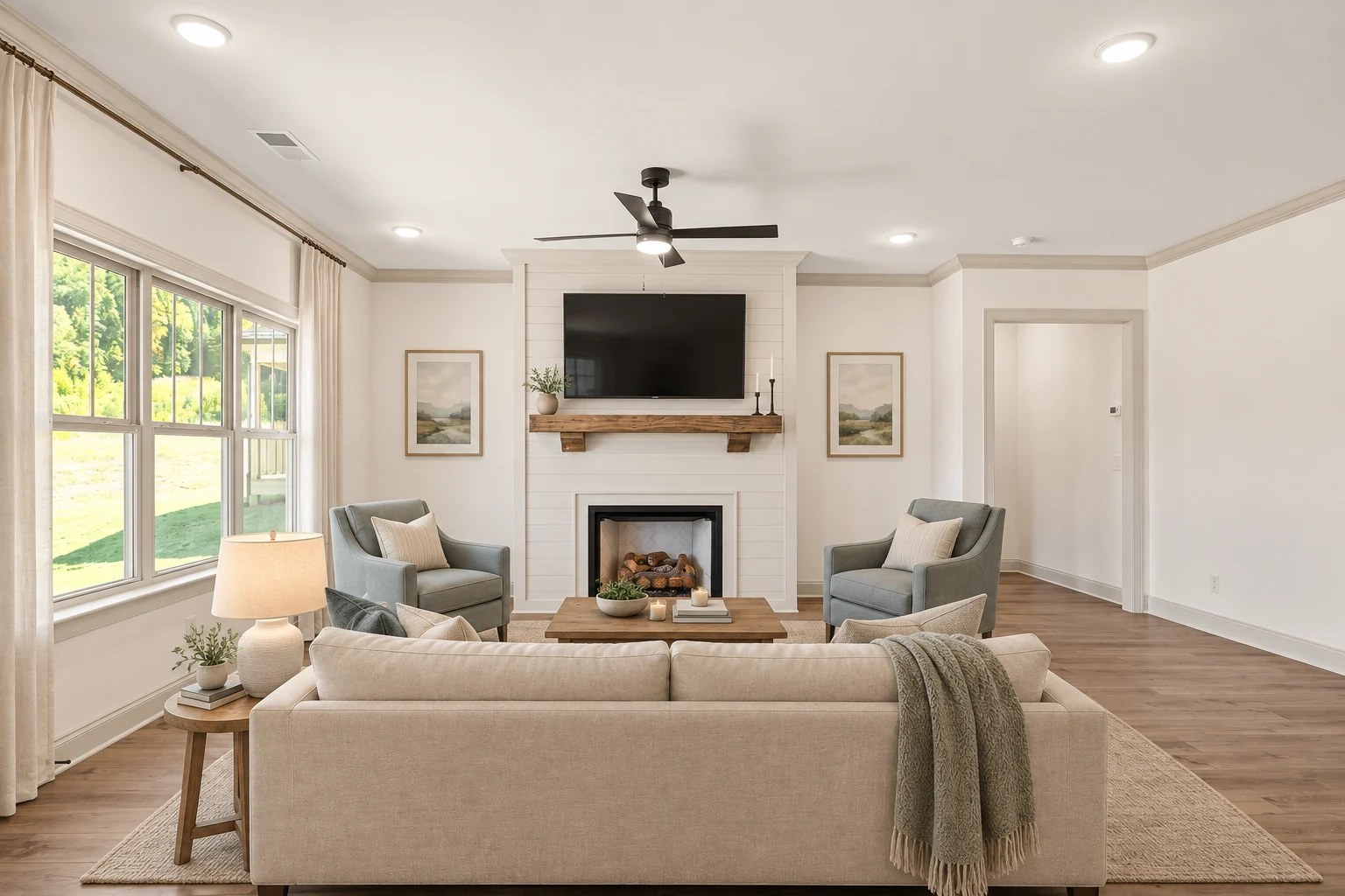 Modern living room by Pratt Home Builders in Chattanooga TN, featuring a fireplace, beige sofa, two gray chairs, and a large window.