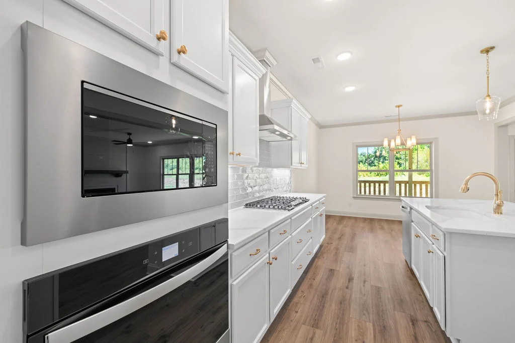 Modern kitchen with white cabinetry, stainless steel appliances, and marble countertops. Design by Pratt Home Builders in Chattanooga TN.