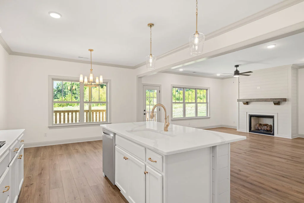 Spacious open-concept kitchen and living area by Pratt Home Builders in Chattanooga TN, featuring white cabinetry, island, and a fireplace.