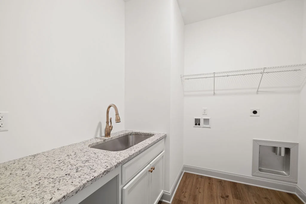 Laundry room by Pratt Home Builders in Chattanooga TN, featuring a granite countertop, sink, and wire shelving.