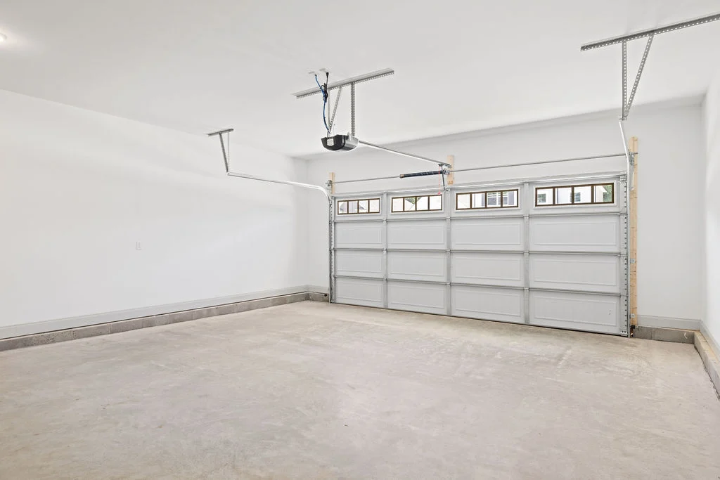 Spacious, clean garage interior with white walls and a double garage door, built by Pratt Home Builders in Chattanooga TN.