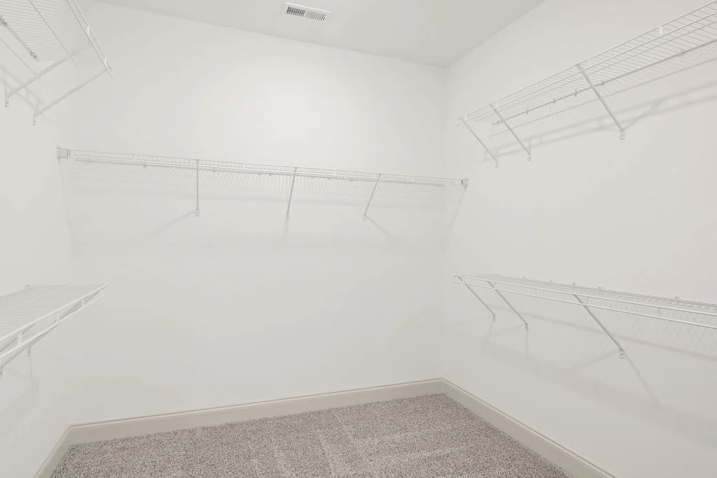 Spacious white closet with wire shelving by Pratt Home Builders in Chattanooga TN, featuring a vented ceiling and carpeted floor.
