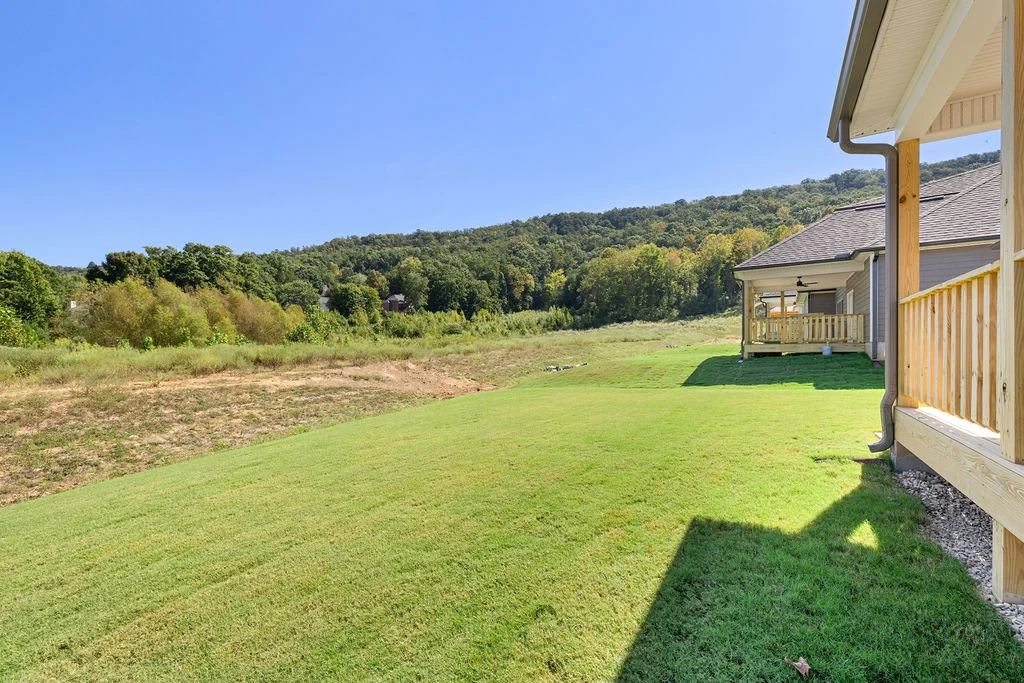 Spacious backyard with lush grass and scenic wooded hills, adjacent to a porch by Pratt Home Builders in Chattanooga, TN.