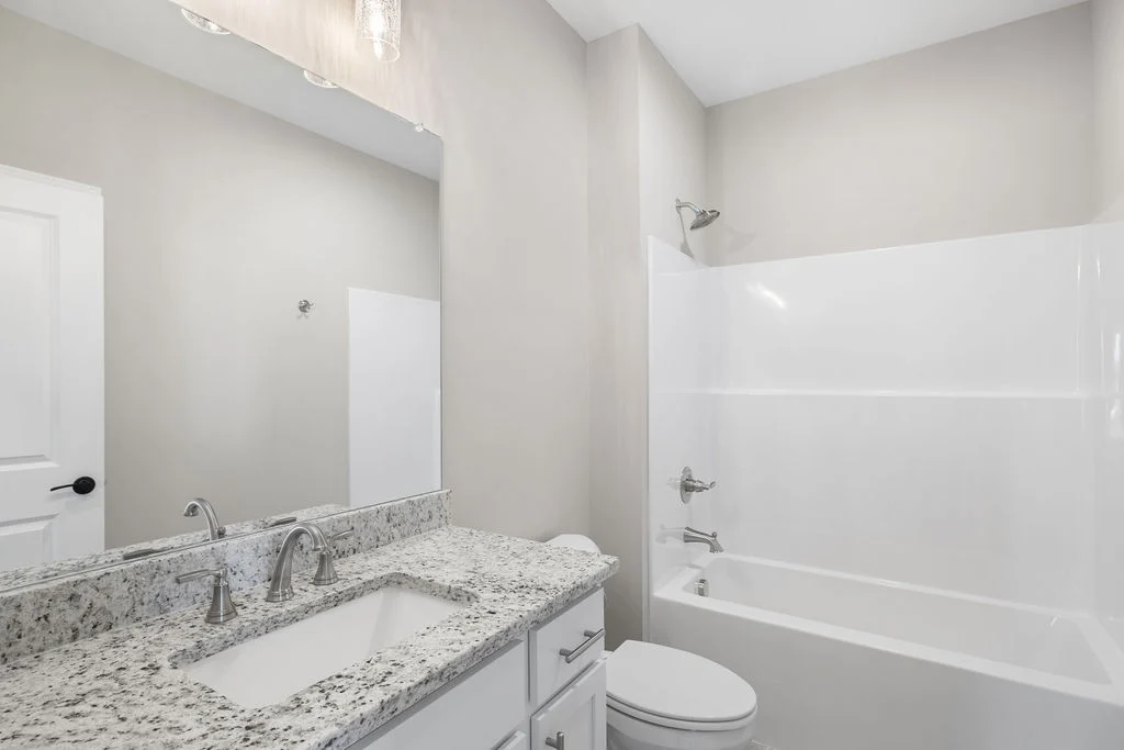Modern bathroom featuring a granite countertop with dual sinks and a bathtub, designed by Pratt Home Builders in Chattanooga TN.