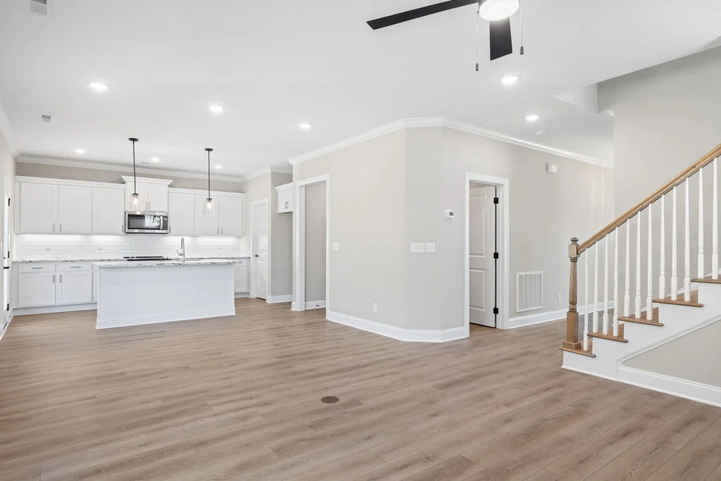 Open-concept living area with hardwood floors, modern kitchen, pendant lights, and staircase. Crafted by Pratt Home Builders in Chattanooga TN.