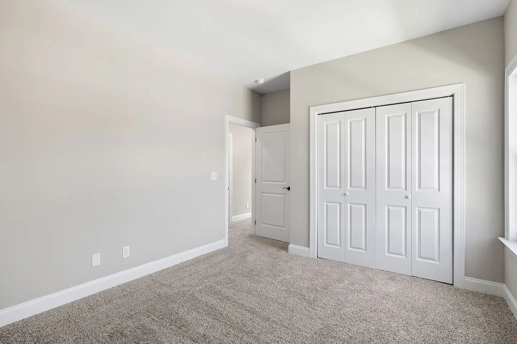 Empty room with gray walls, carpeted floor, and white double closet doors. Built by Pratt Home Builders in Chattanooga TN.