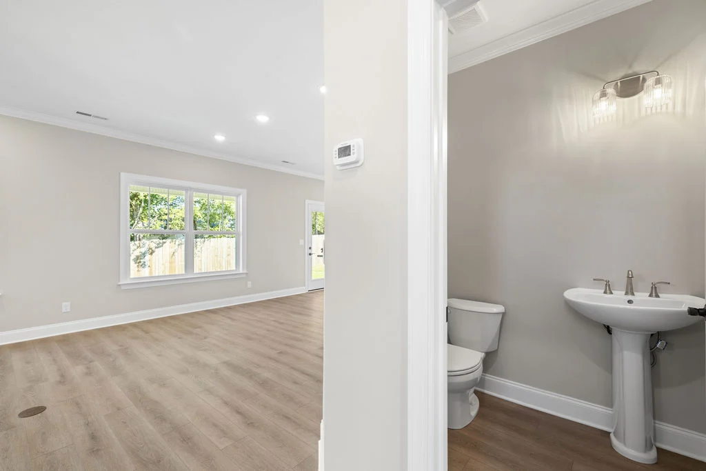 Modern open-concept living area with wood floors, adjacent bathroom; built by Pratt Home Builders in Chattanooga TN.