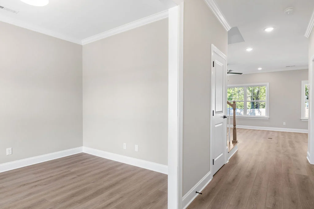 Spacious empty room with beige walls, wood flooring, and large windows. Crafted by Pratt Home Builders in Chattanooga TN.