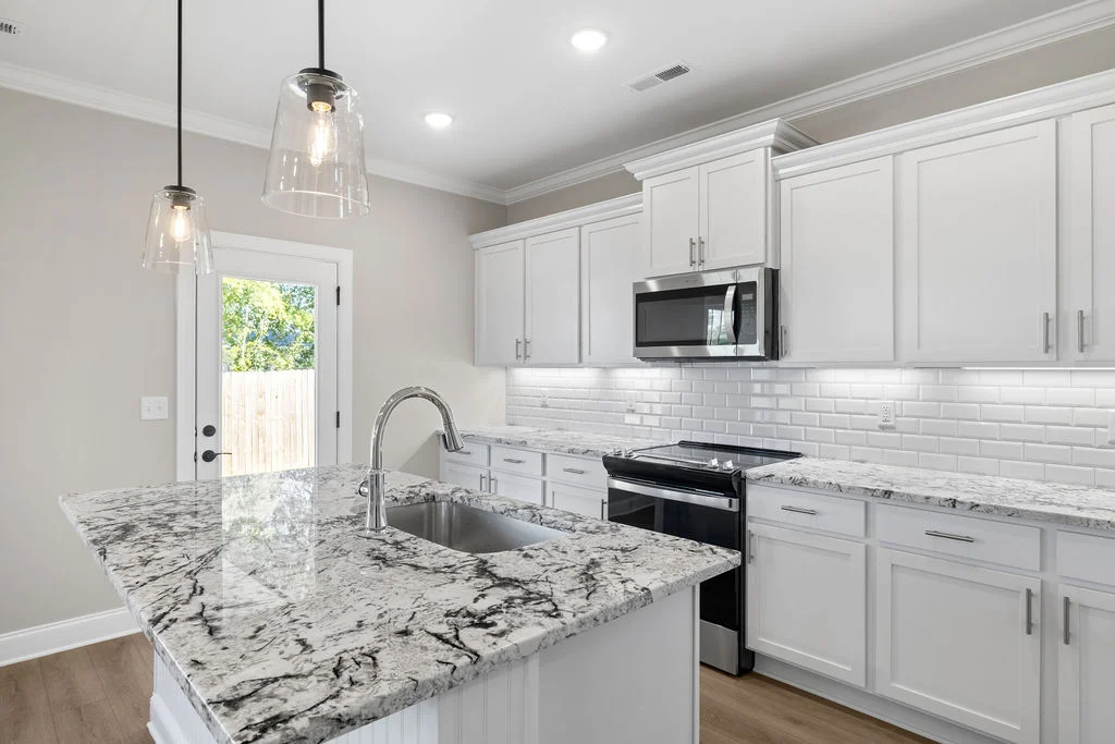 Modern kitchen with marble island, pendant lights, white cabinets, and subway tiles by Pratt Home Builders in Chattanooga TN.