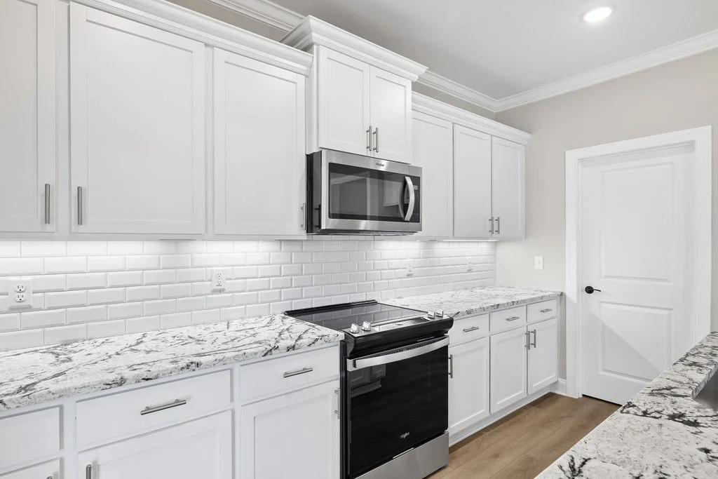 Modern kitchen with white cabinets, marble countertops, and subway tile backsplash. Stainless steel appliances. Pratt Home Builders in Chattanooga TN.