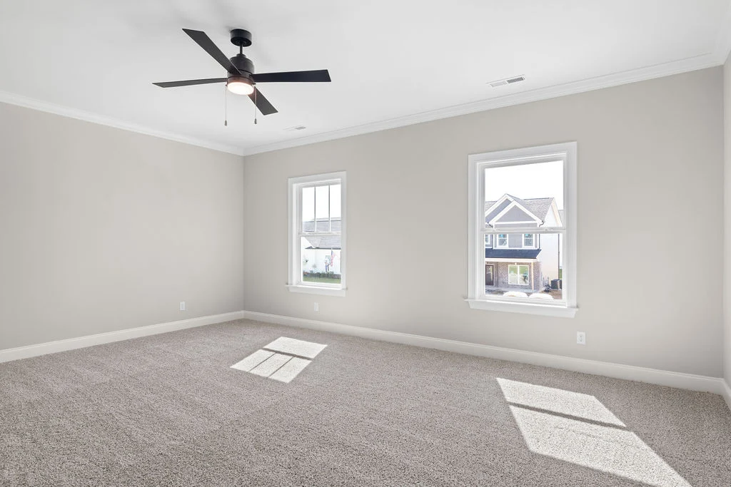 Empty carpeted room with two windows, a ceiling fan, and neutral walls, showcasing Pratt Home Builders in Chattanooga TN craftsmanship.