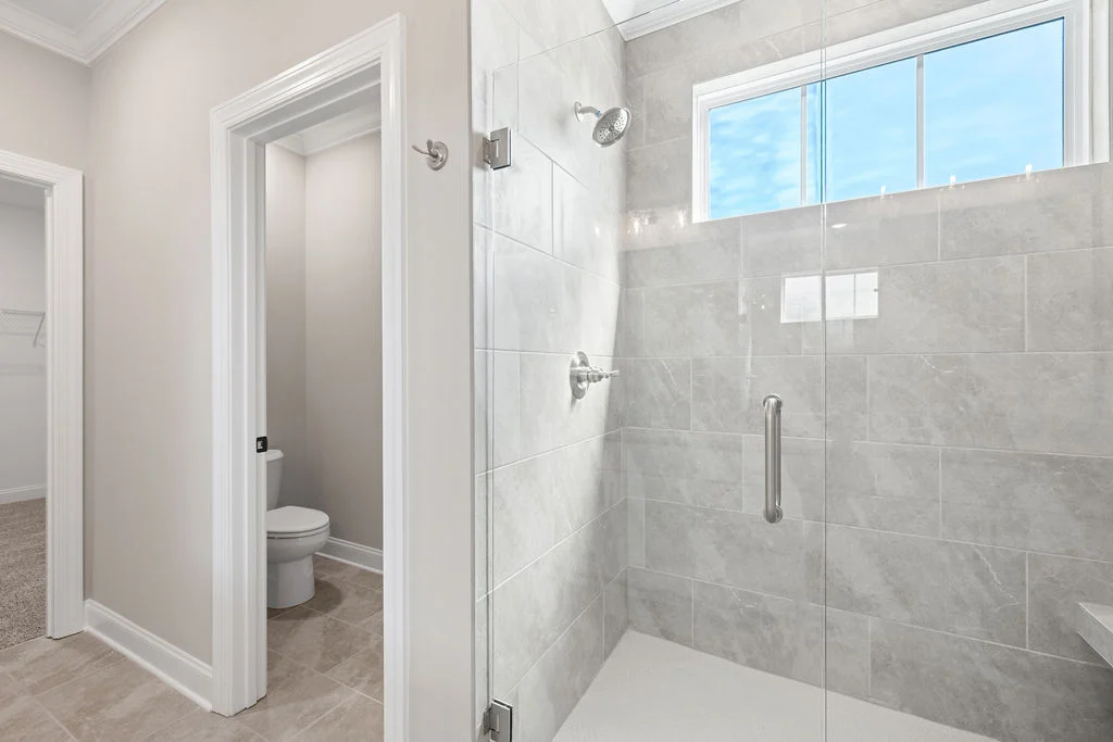 Modern bathroom featuring a glass-enclosed shower, adjacent toilet, and neutral tones, designed by Pratt Home Builders in Chattanooga TN.