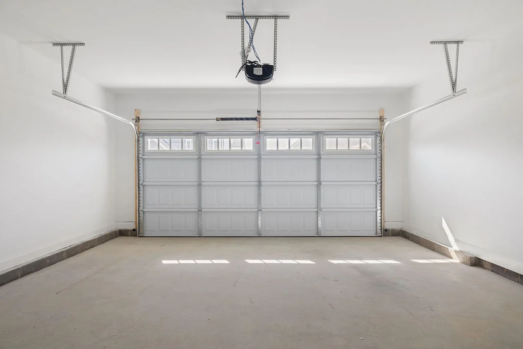 Spacious, clean, empty garage with a closed door and overhead motor, built by Pratt Home Builders in Chattanooga TN.