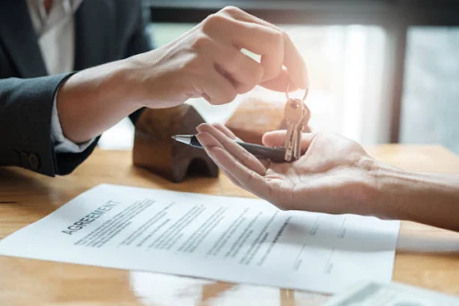 unnamed (1) Keys exchanged over a signed agreement on a wooden table, symbolizing a completed home sale by Pratt Home Builders in Chattanooga TN.