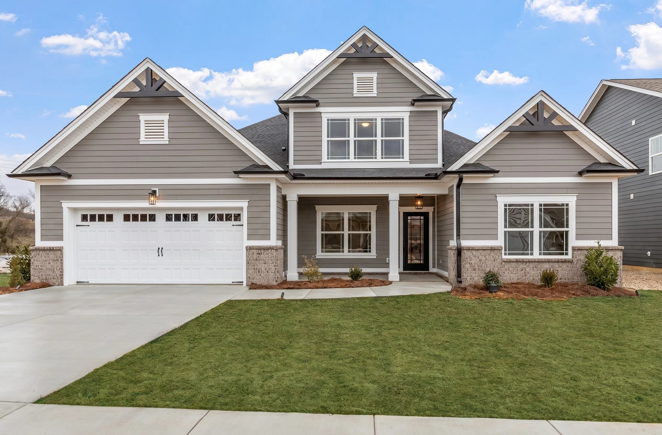 Modern grey suburban house with white trim, two-story design, and manicured lawn. Built by Pratt Home Builders in Chattanooga TN.