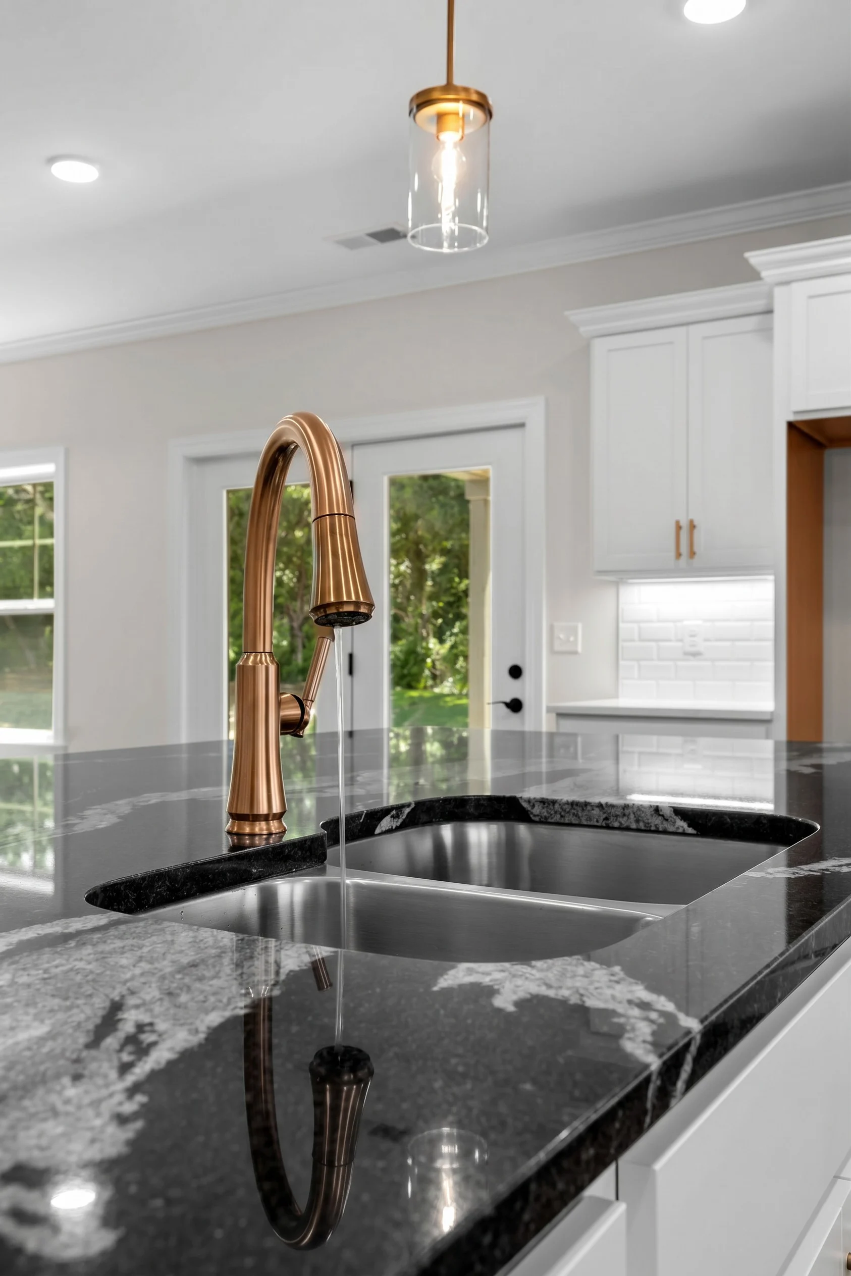 Modern kitchen with marble countertop, bronze faucet streaming water, and elegant cabinetry, crafted by Pratt Home Builders in Chattanooga TN.