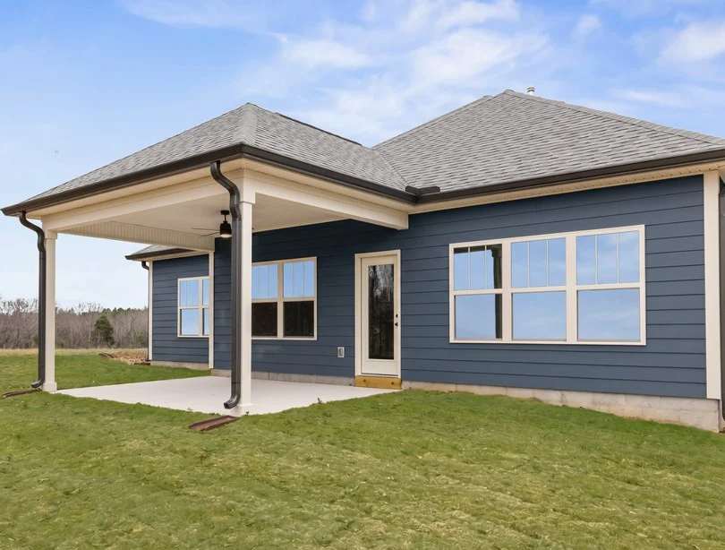 Modern blue home exterior with large windows and a covered patio on a green lawn, built by Pratt Home Builders in Chattanooga TN.