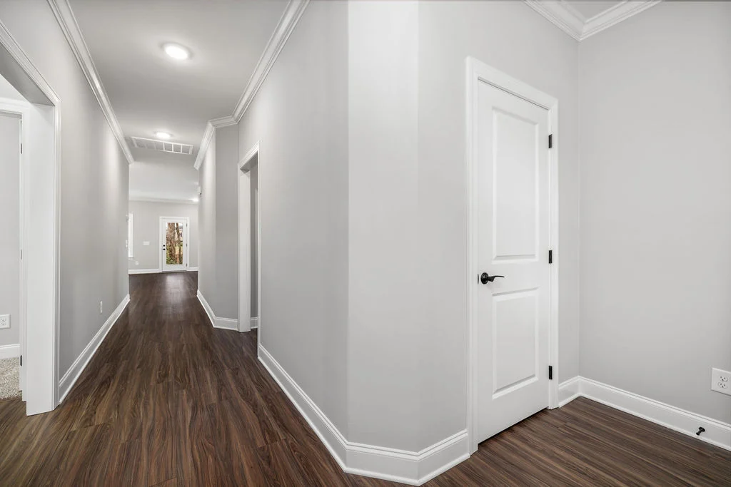 Modern hallway with wooden floors and beige walls by Pratt Home Builders in Chattanooga TN, featuring white doors and crown molding.