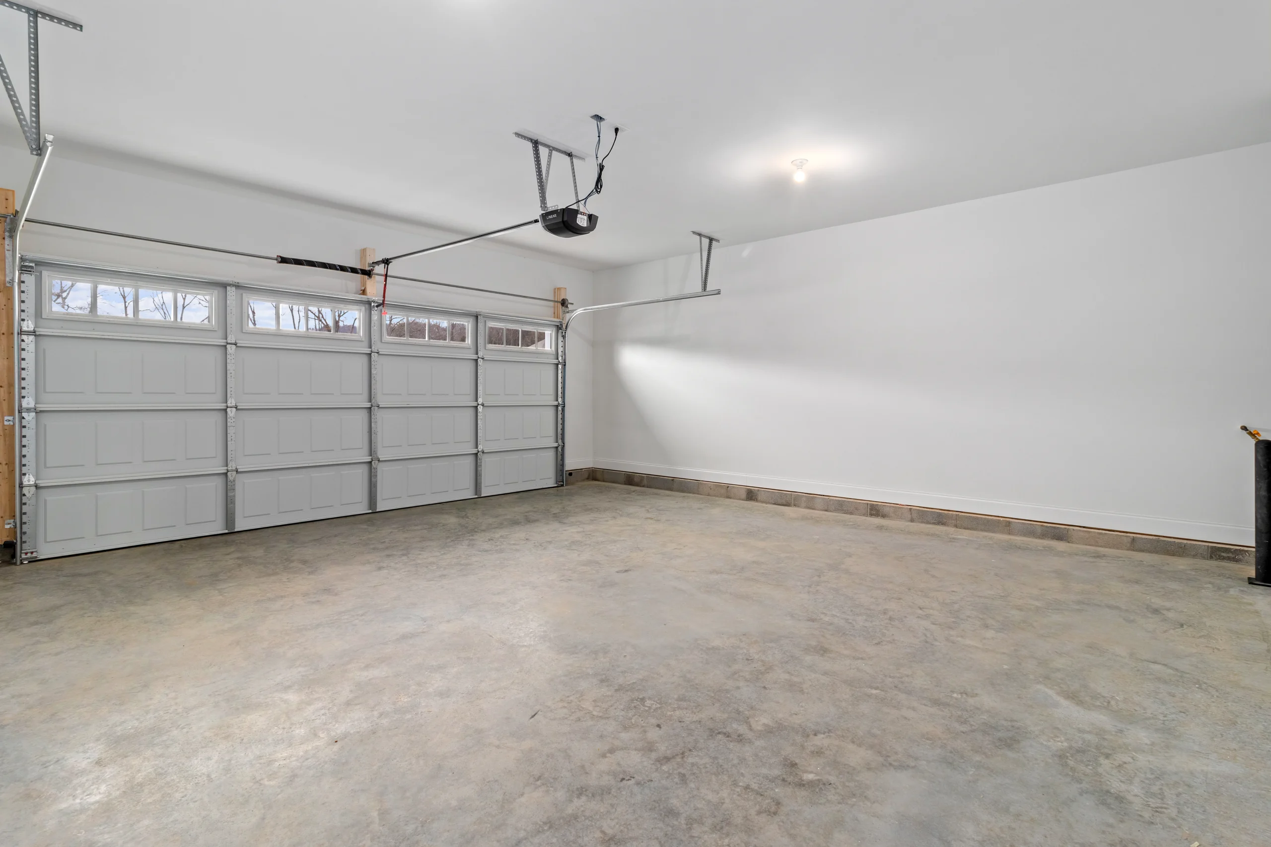 Spacious, clean three-car garage with gray doors, created by Pratt Home Builders in Chattanooga TN.