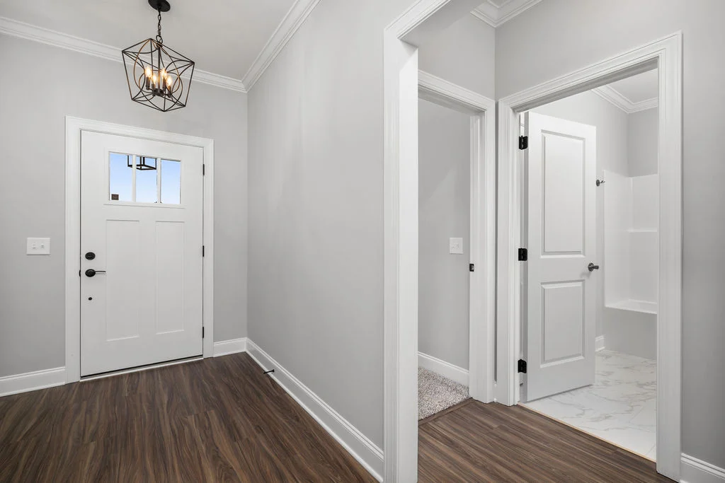 Entryway featuring gray walls, wood floors, and modern lighting. View of white bathroom door, crafted by Pratt Home Builders in Chattanooga TN.
