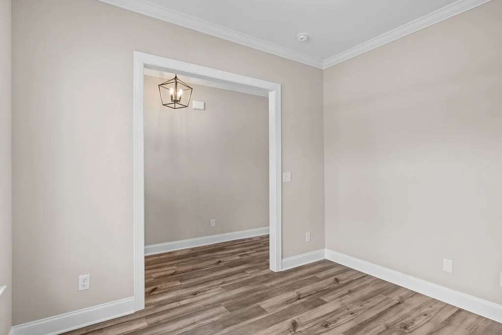 Elegant room with wood flooring, neutral walls, white trim, and a geometric pendant light. By Pratt Home Builders in Chattanooga TN.