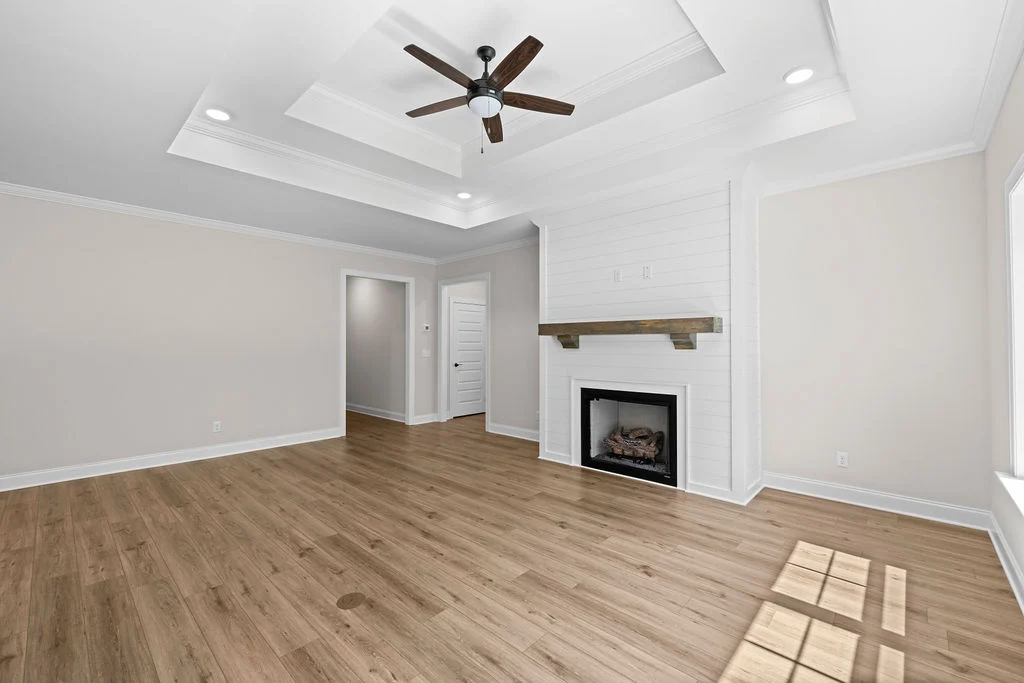 Modern living room by Pratt Home Builders in Chattanooga TN, featuring coffered ceiling, fan, shiplap fireplace, and light wood flooring.