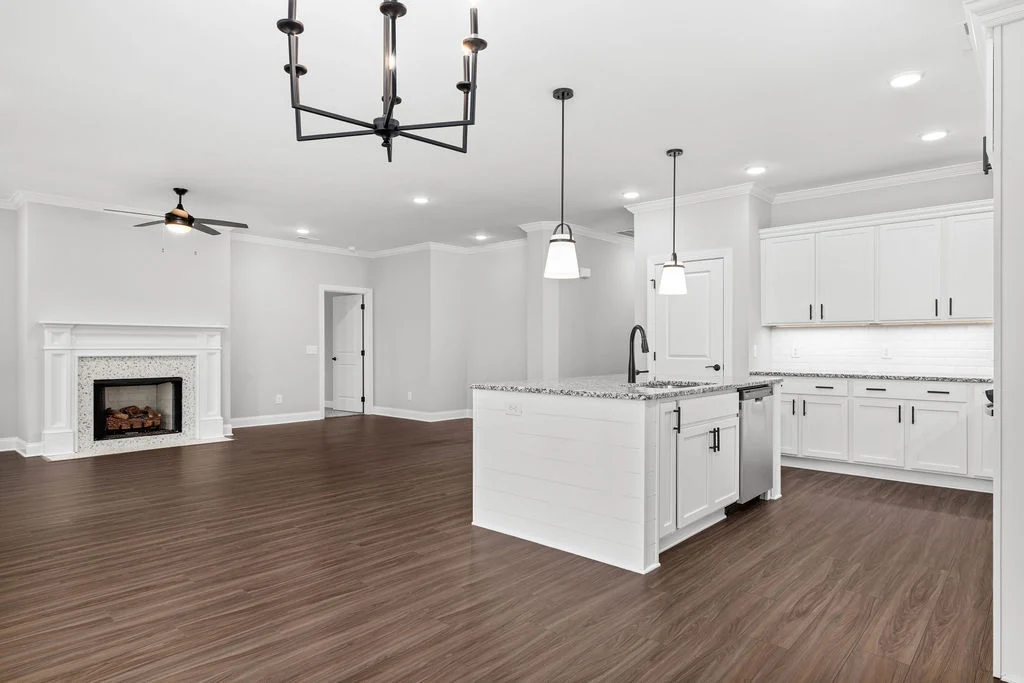 Open-concept living area by Pratt Home Builders in Chattanooga TN, featuring a modern kitchen, hardwood floors, and a white fireplace.