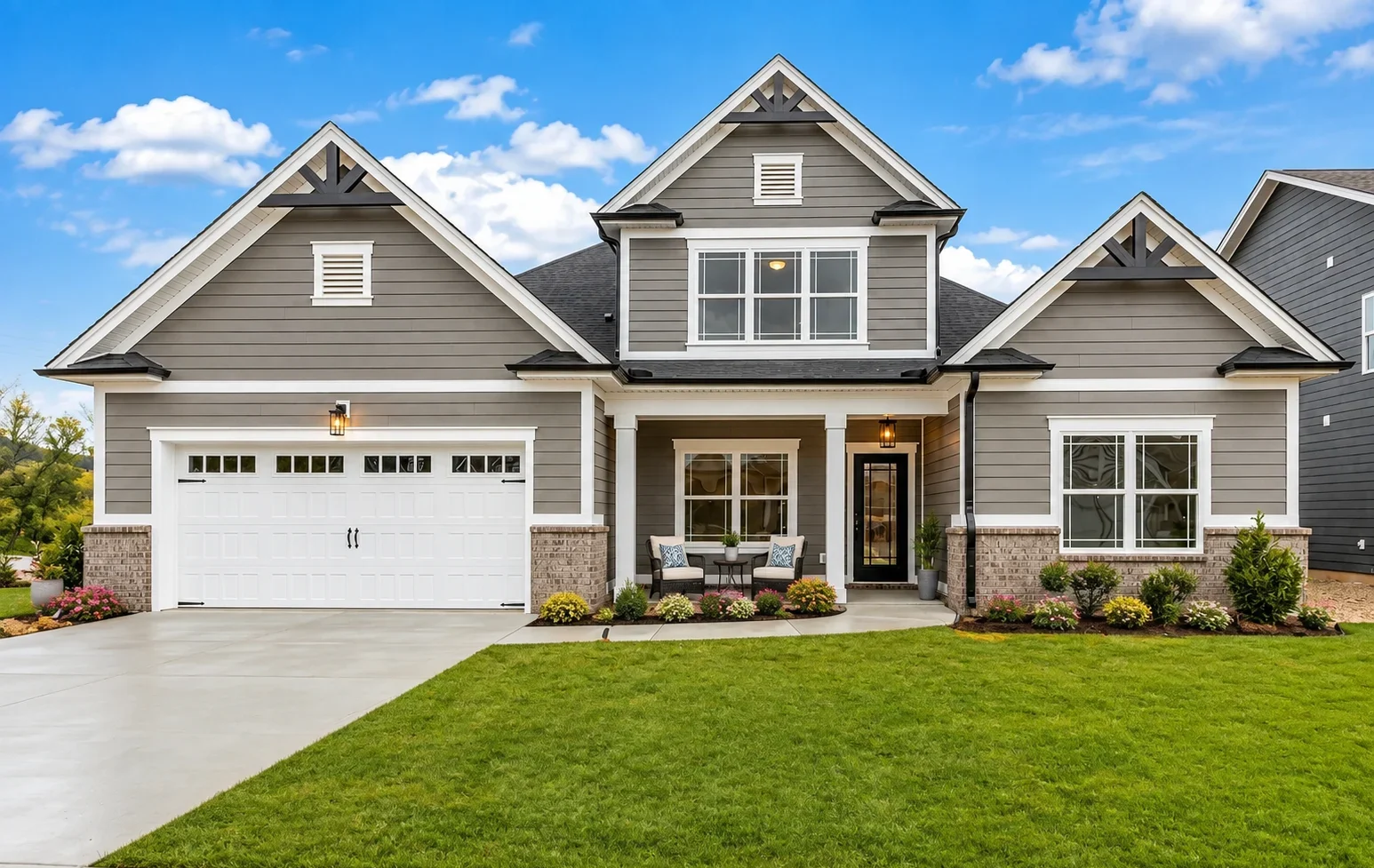 Modern two-story home with gray siding, white trim, and inviting porch. Built by Pratt Home Builders in Chattanooga TN. Lush green lawn in front.