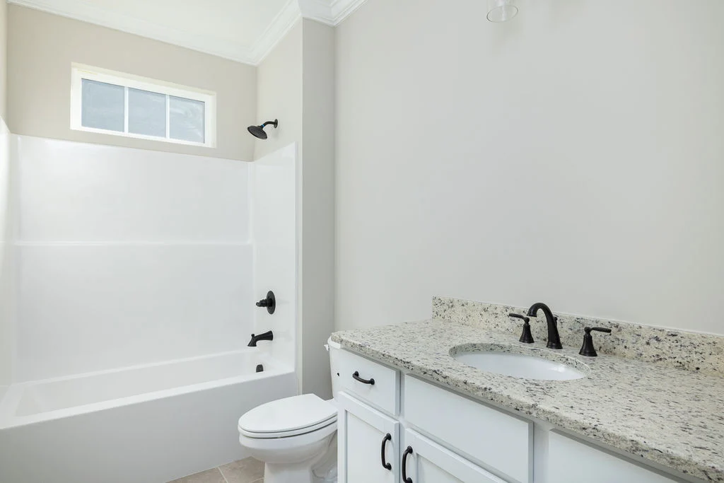 Modern bathroom with granite countertop, white cabinets, and bathtub by Pratt Home Builders in Chattanooga TN.