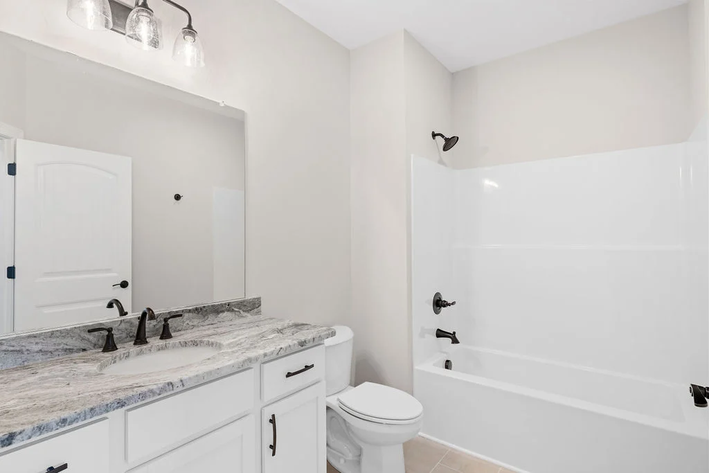 Modern bathroom with marble countertop, white cabinets, and bathtub, designed by Pratt Home Builders in Chattanooga TN.