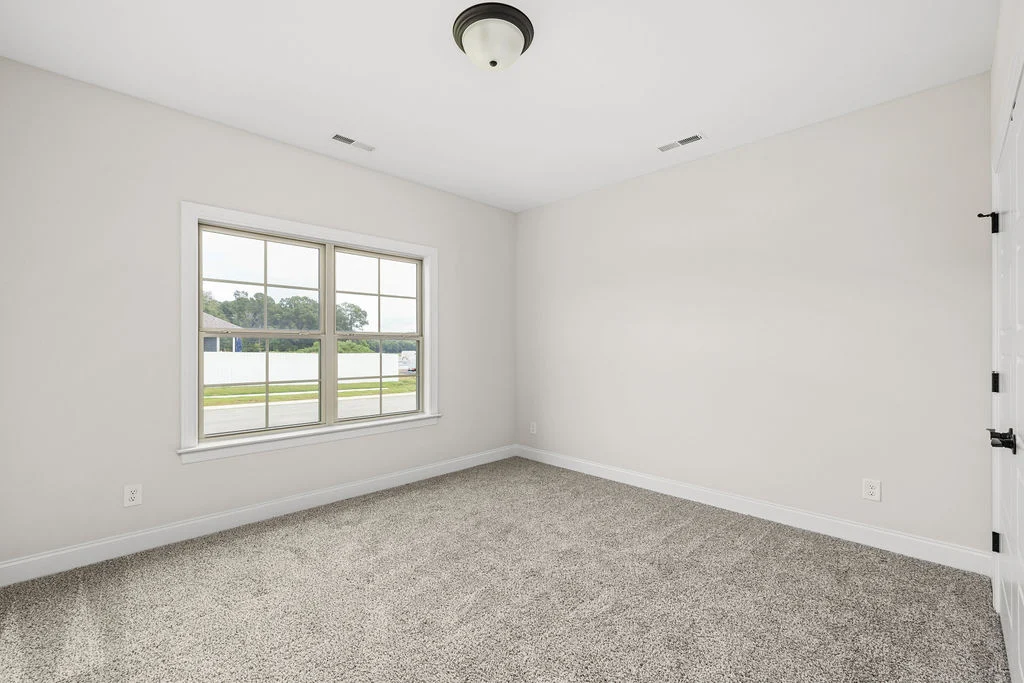 Bright, empty room with gray carpet, large window, and white walls, showcasing Pratt Home Builders in Chattanooga TN's new construction.