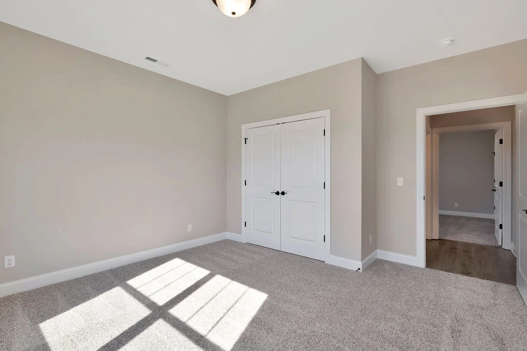 Neutral-toned room with carpet, double door closet, and hallway. Featured design by Pratt Home Builders in Chattanooga TN.