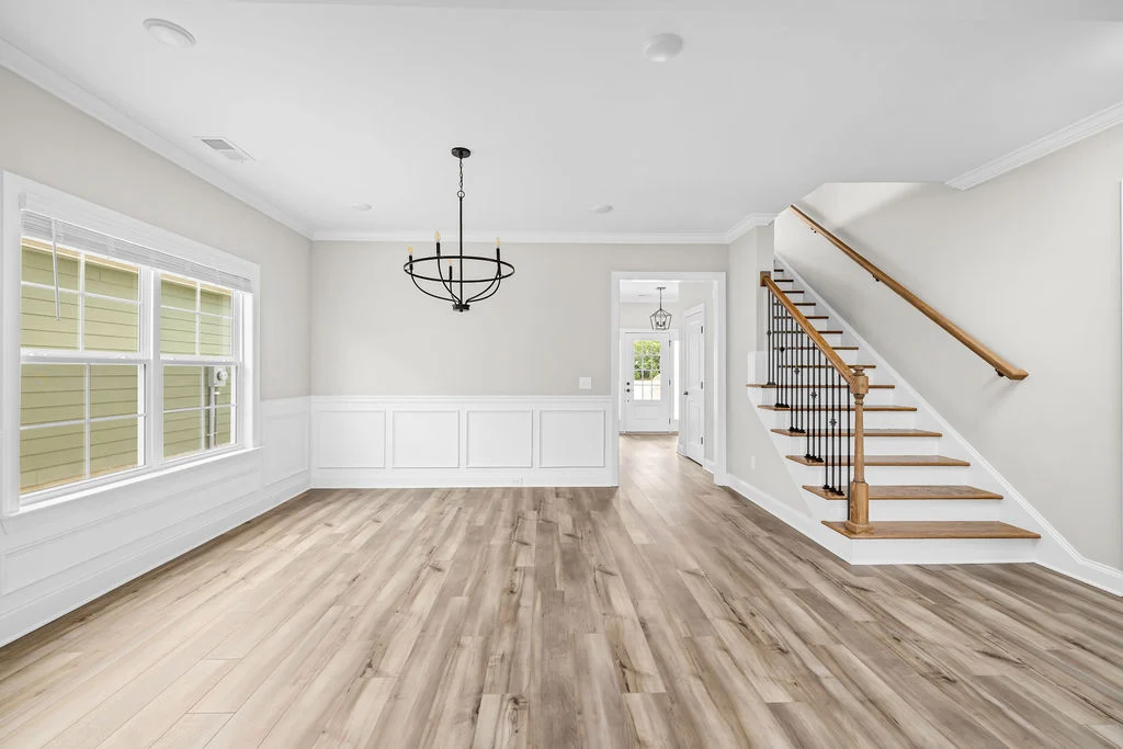 Bright, modern entryway with light wood floors, black chandelier, and wooden staircase. Pratt Home Builders in Chattanooga TN craftsmanship.